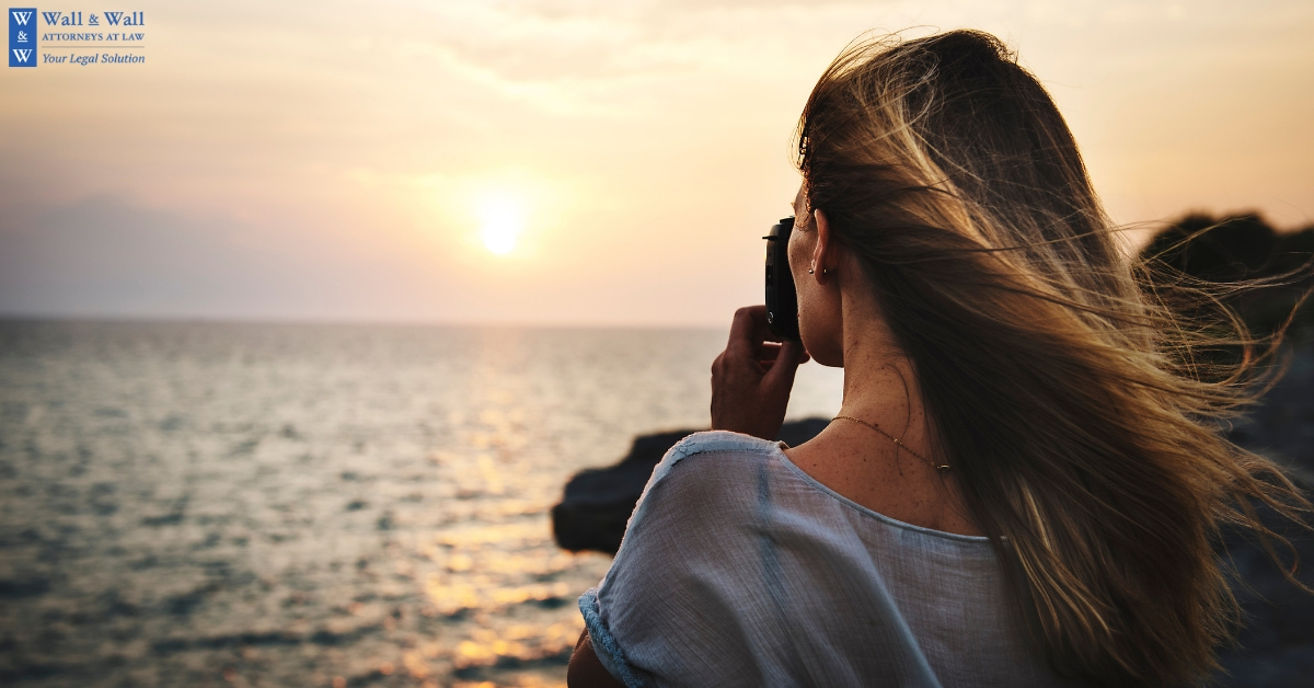 Woman taking picture of sun setting over sea